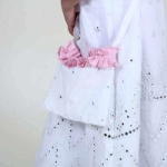 صورة فستان قرقيعان مزين بالترتر باللونين الأبيض والوردي مع عصابة رأس وحقيبة كتف لحديثي الولادة