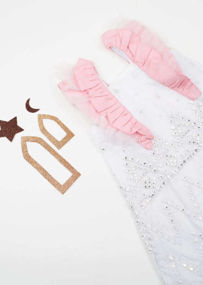 صورة فستان قرقيعان مزين بالترتر باللونين الأبيض والوردي مع عصابة رأس وحقيبة كتف لحديثي الولادة
